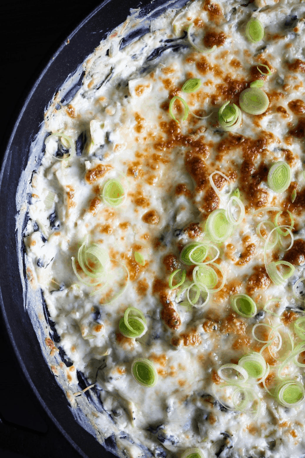 Close-up top down shot of spinach artichoke dip in a cast-iron skillet. 