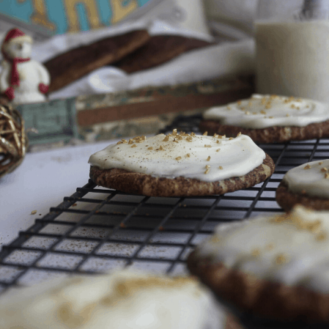 Eggnog snickerdoodles on wire cooling rack with eggnog in and Christmas decor in background.