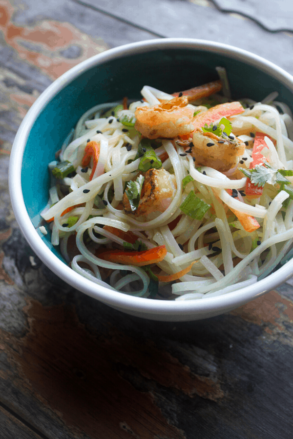 tossed spring roll bowls with shrimp and ginger garlic lime sauce in blue bowl on wood surface