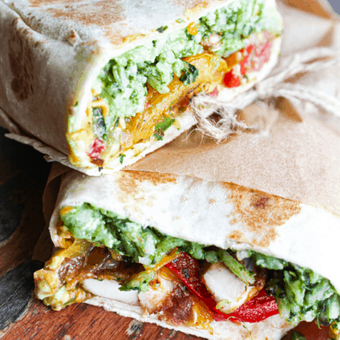 two halves of chicken fajita wraps stacked atop each other on wooden surface