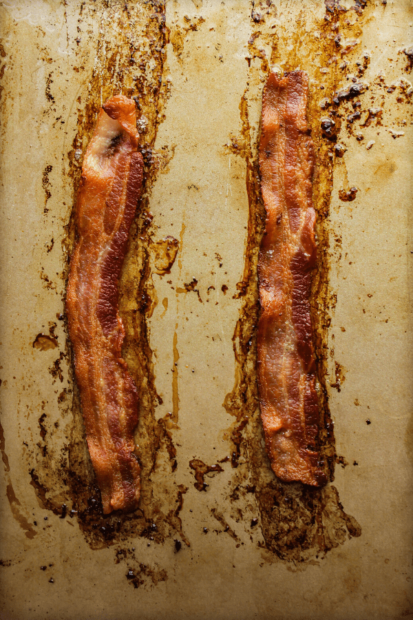 two strips of cooked bacon on a sheet pan from above 