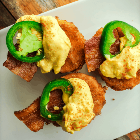 deep fried jalapeno popper deviled eggs on white tray atop distressed wood table