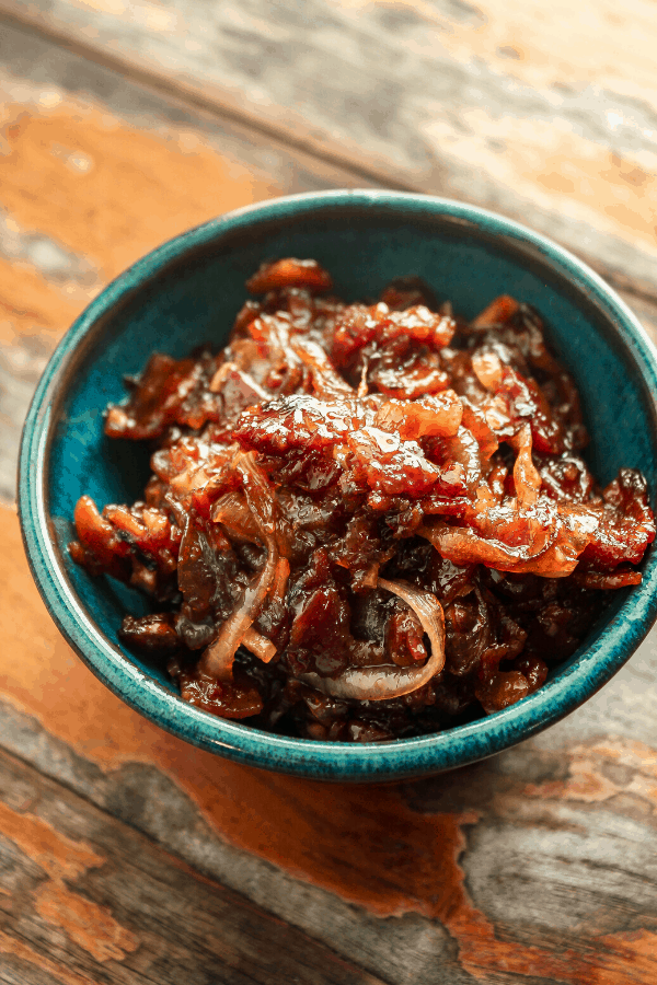 bacon onion jam in blue bowl on distressed wood surface 
