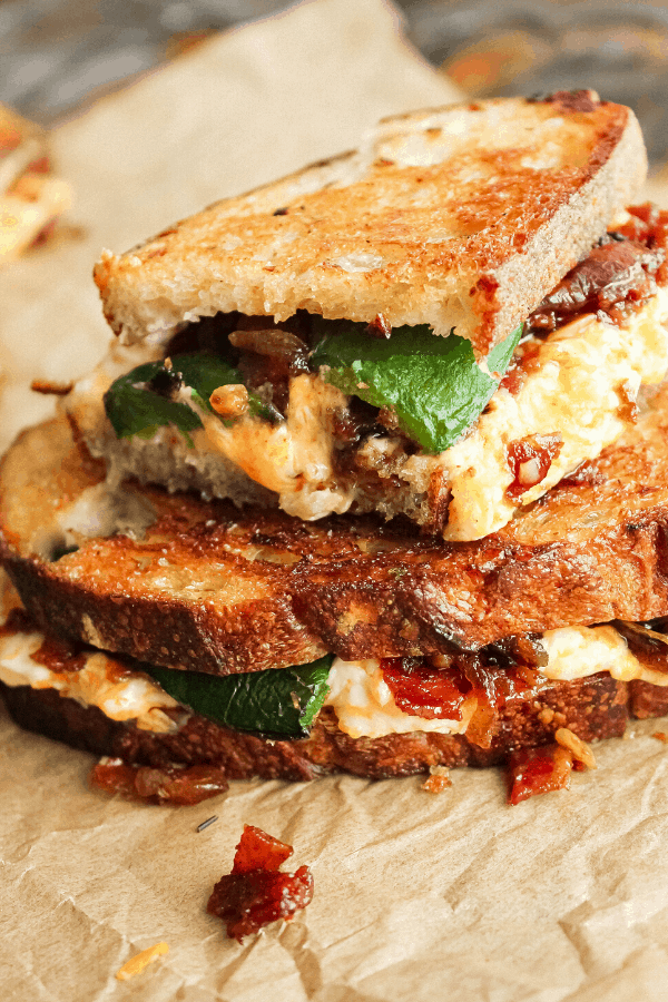 half jalapeno popper grilled cheese w/ bacon jam atop a full sandwich on parchment paper