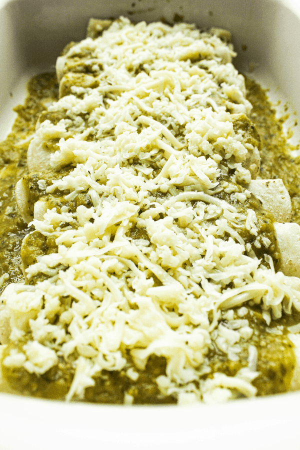 enchiladas covered with sauce and cheese in baking dish prior to cooking 