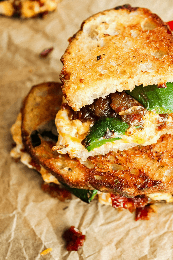 close up of half jalapeno popper grilled cheese w/ bacon jam atop a full sandwich from above 