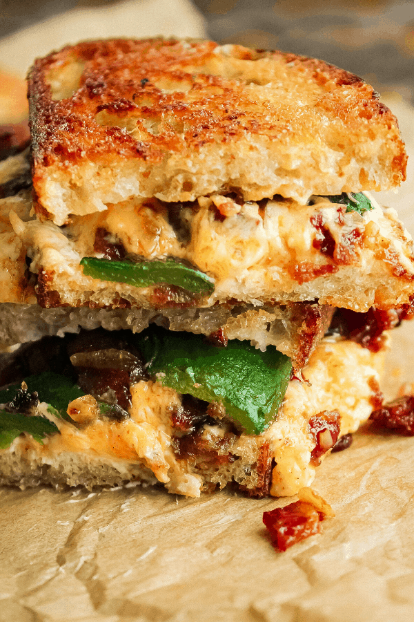 close up of two halves of jalapeno popper grilled cheese w/ bacon jam atop one another 