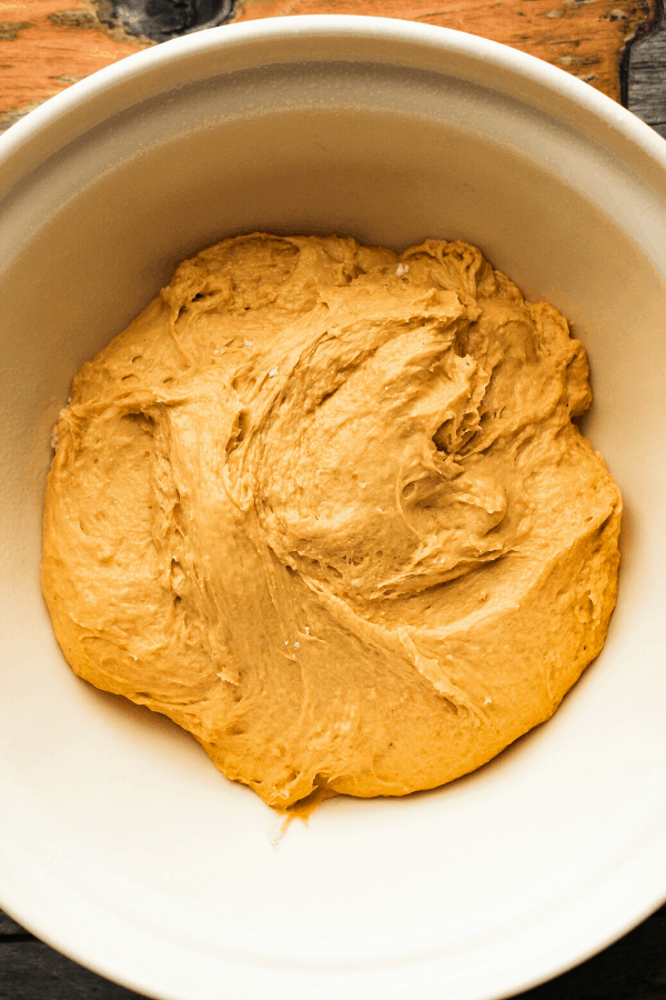 pumpkin cinnamon roll dough in cream bowl from above