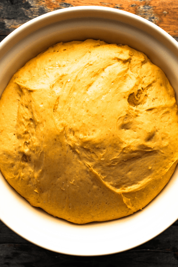 pumpkin cinnamon rolls dough after rising in cream bowl 
