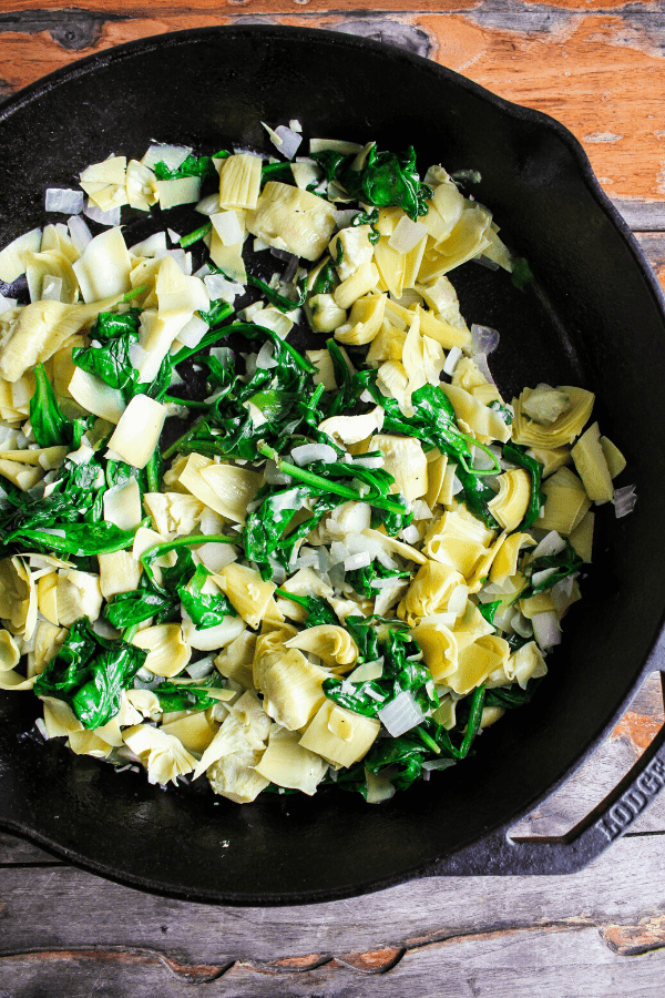 Sautéd spinach and artichoke mixture in cast-iron skillet shot from above. 