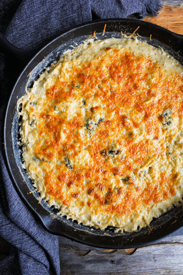 Full baked spinach artichoke casserole in cast-iron skillet shot from above. 