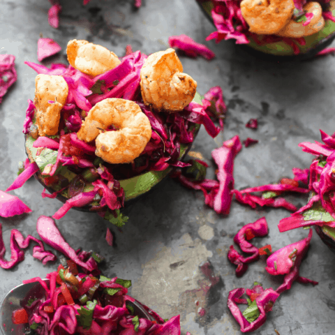 Mexican slaw & shrimp stuffed avocados on baking sheet with spoon of slaw shot from above