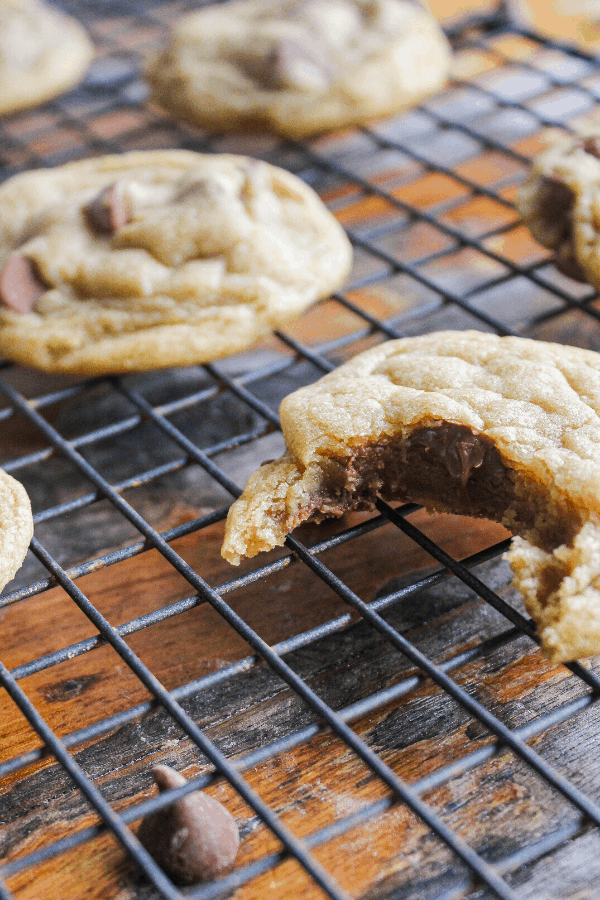 Close up of chocolate chip cookies with bite out of it on wire cooling rack with additional cookies. 