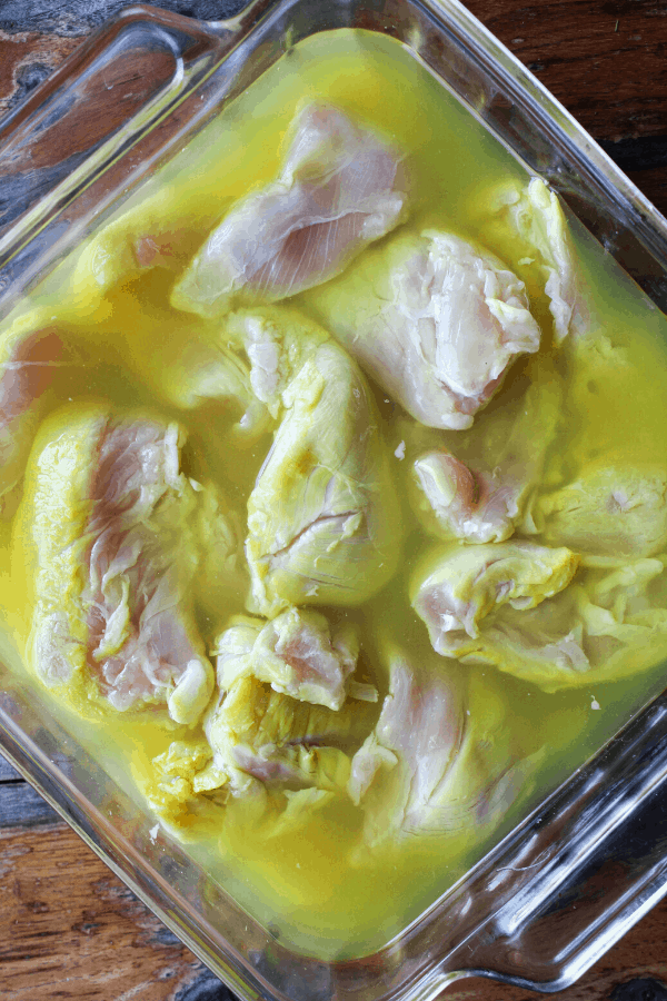 Chicken tenderloins in baking dish submerged in pickle brine shot from above.