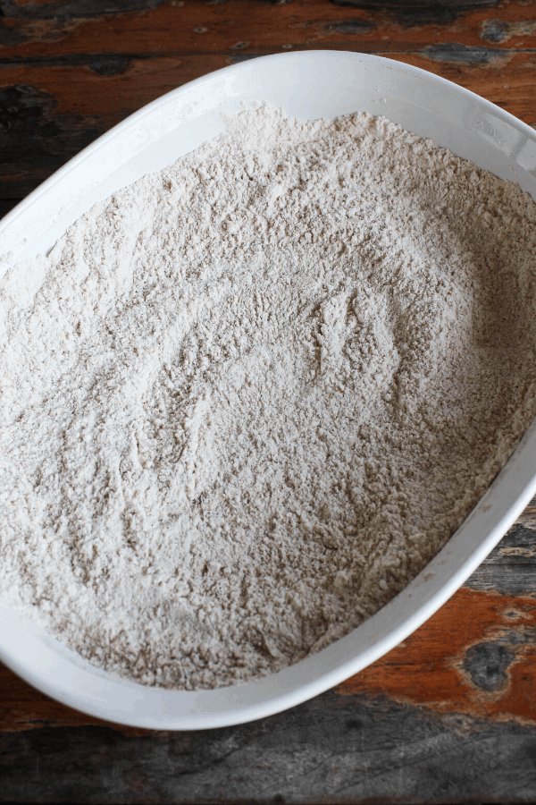 Flour coating for chicken tenders in a baking dish shot from above. 
