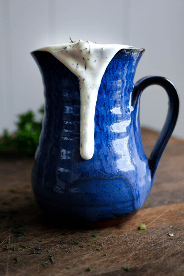 Ranch in blue vase dripping down side with herbs in background. 