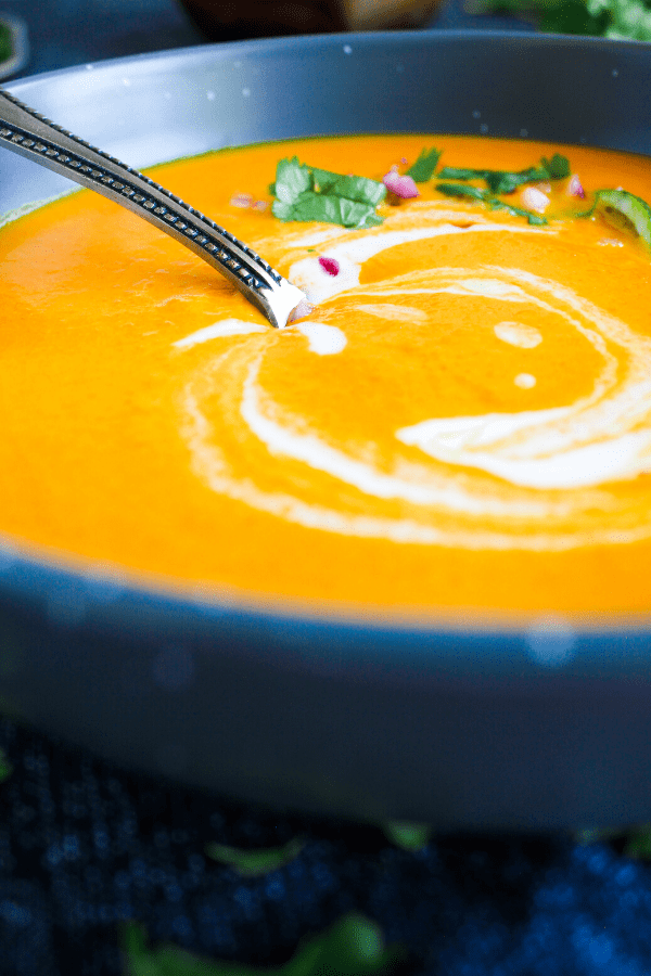 Bowl of carrot soup with spoon shot from front. 