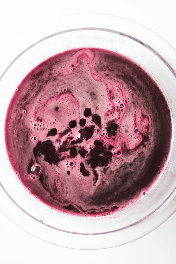 Top down shot of blueberry basil simple syrup in a clear bowl. 