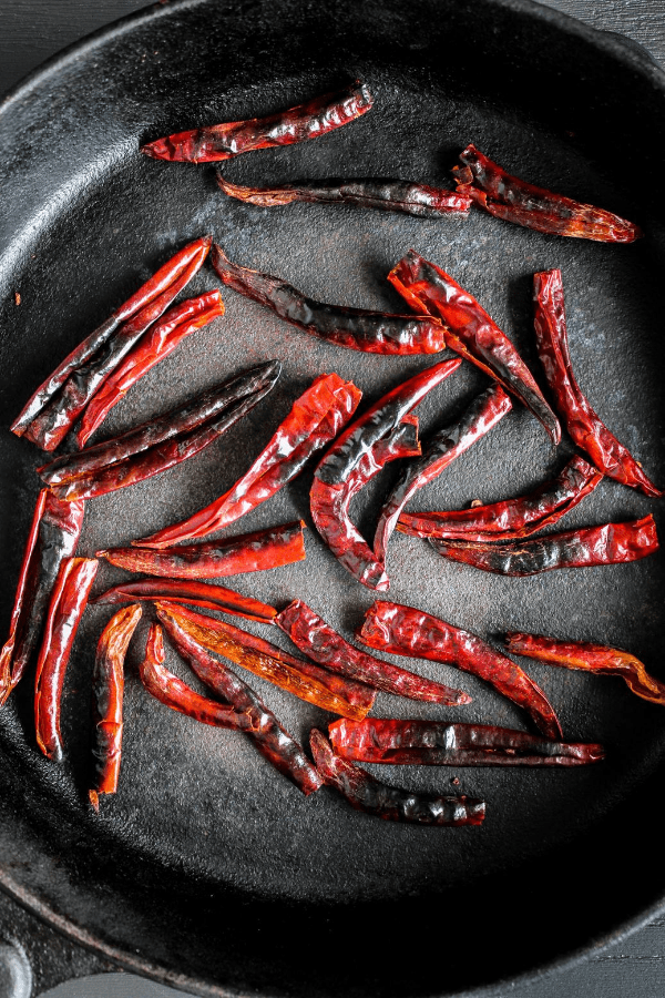 Top down shot of toasted chiles in a skillet. 