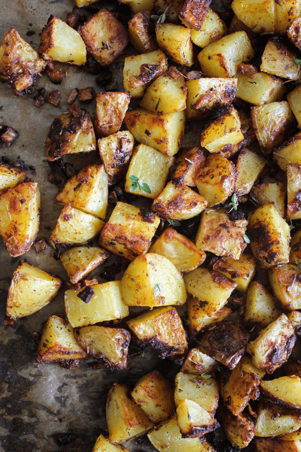 Roasted French onion potatoes on a baking sheet sprinkled with fresh thyme shot from above. 