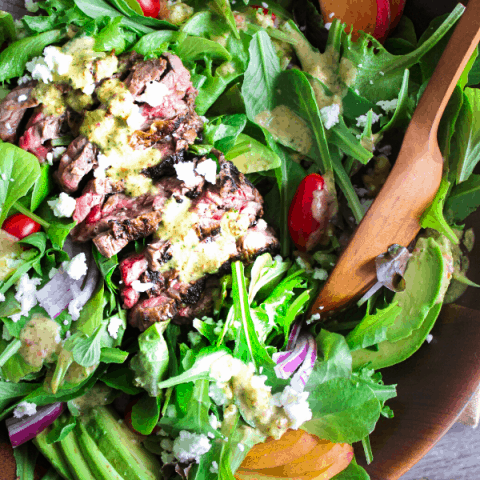 Walnut bowl filled with grilled steak salad dressed in habanero peach dressing shot from above.