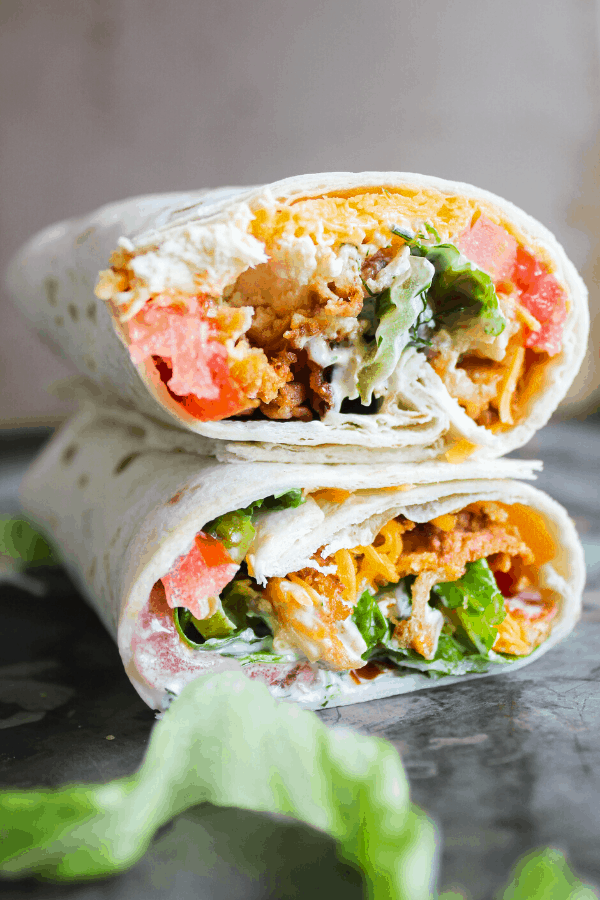 Close up front shot of two halves of a pickle-brined fried chicken wraps. 