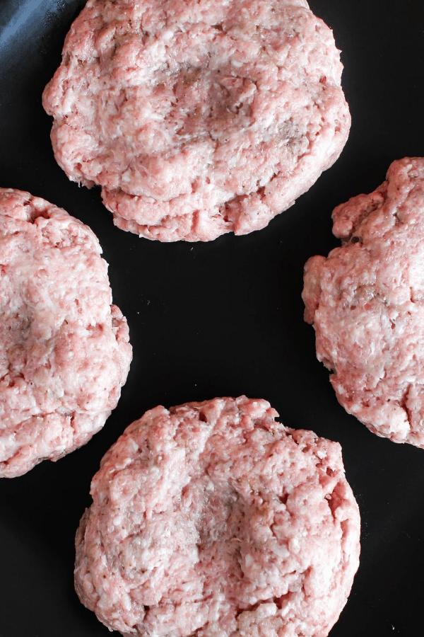 Top down shot of burger patties on a black surface. 