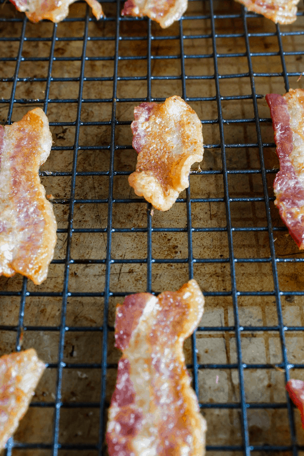 Bacon slices on a wire cooling rack atop a baking sheet. 