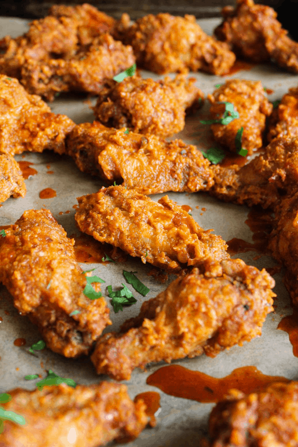 Chile De Árbol Chicken Wings spread out on a platter dripping with sauce and sprinkled with cilantro.