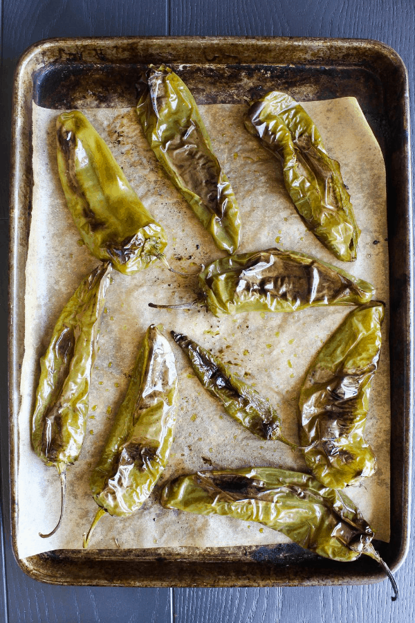 Top down shot of roasted hatch chiles on sheet pan lined with parchment paper.