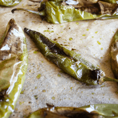 Roasted hatch chiles on a piece of parchment paper.