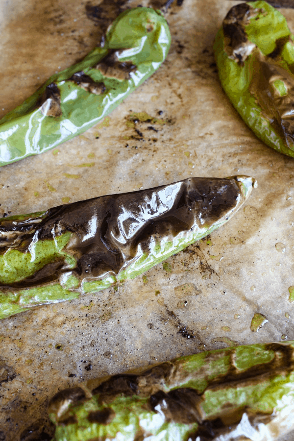 Close-up of roasted hatch chiles on parchment paper.