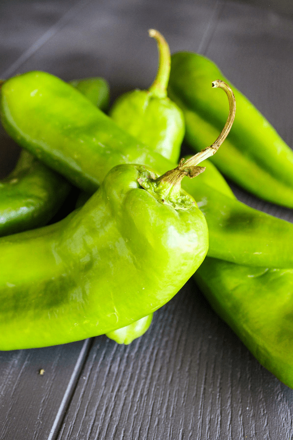 Close-up shot of pile of raw hatch chile peppers. 