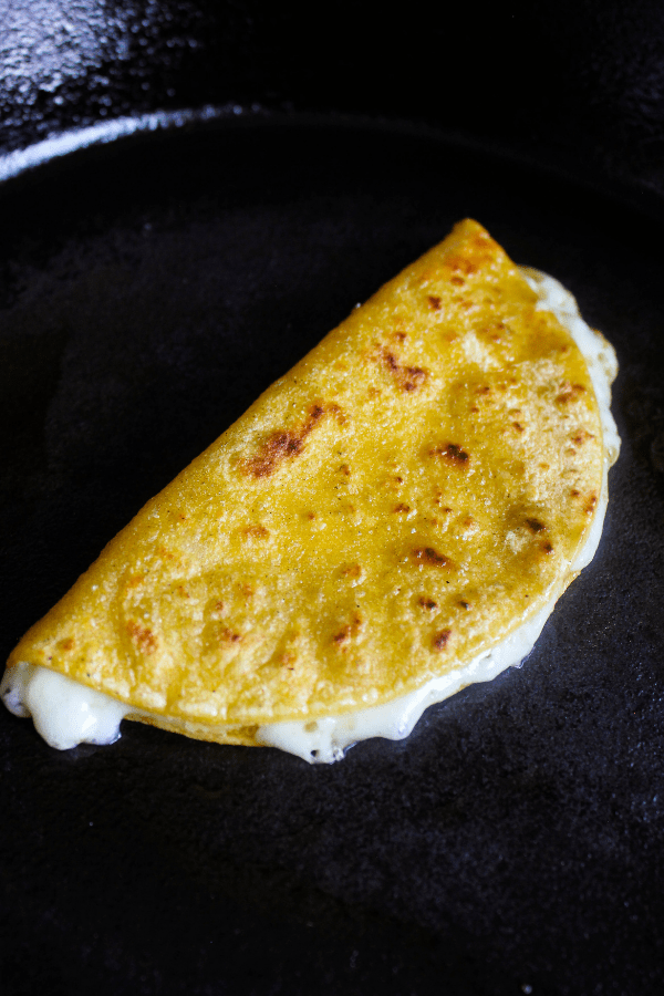 A single cheese quesadilla in a cast-iron skillet.
