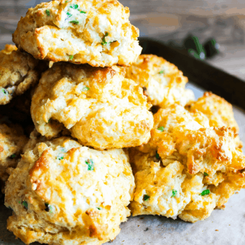 Close-up of stack of jalapeno cheddar drop biscuits with jalapenos in the background.