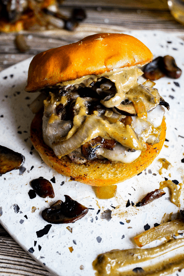 Platter topped with mushroom & Swiss burger with top bun sliding off.
