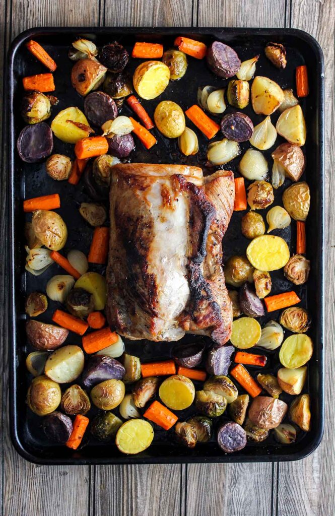 Cooked roast with vegetables on sheet pan.