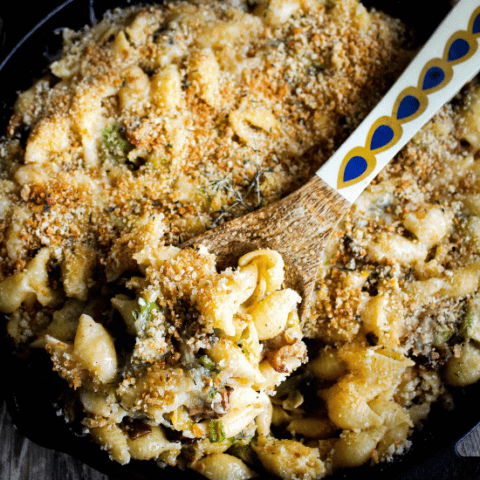 Close-up top down shot of mac and cheese in cast-iron pan with decorative wooden spoon.