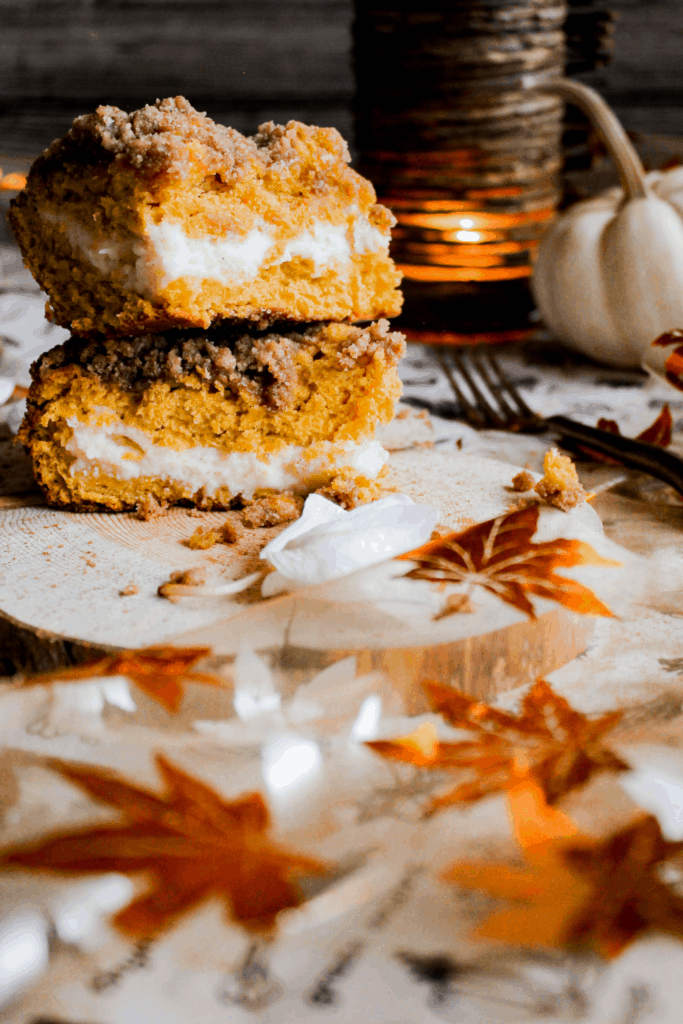 Two slices of cake stacked atop each on a wood platter with fall decorations.