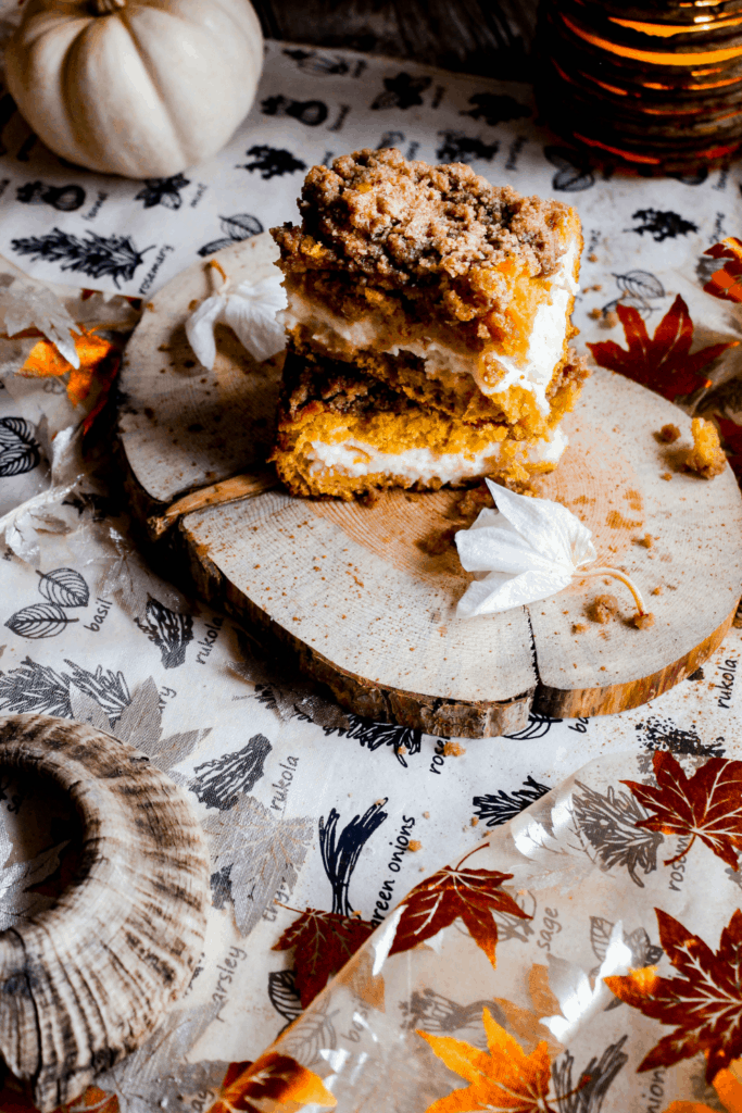 Two pieces of coffee cake on wood plater amongst fall decor.