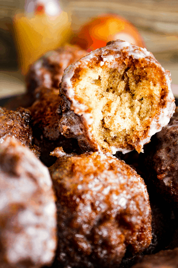 Close up of a bit into vanilla chai donut hole with apple cider glaze atop a stack of donut holes.