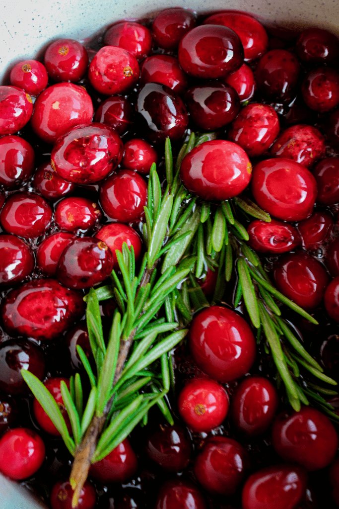 Fresh cranberries and rosemary in saucepan with simple syrup.