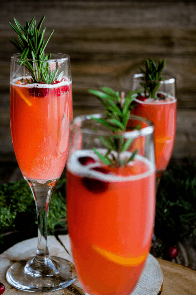 Three glasses of mimosa on wood plants with greenery.