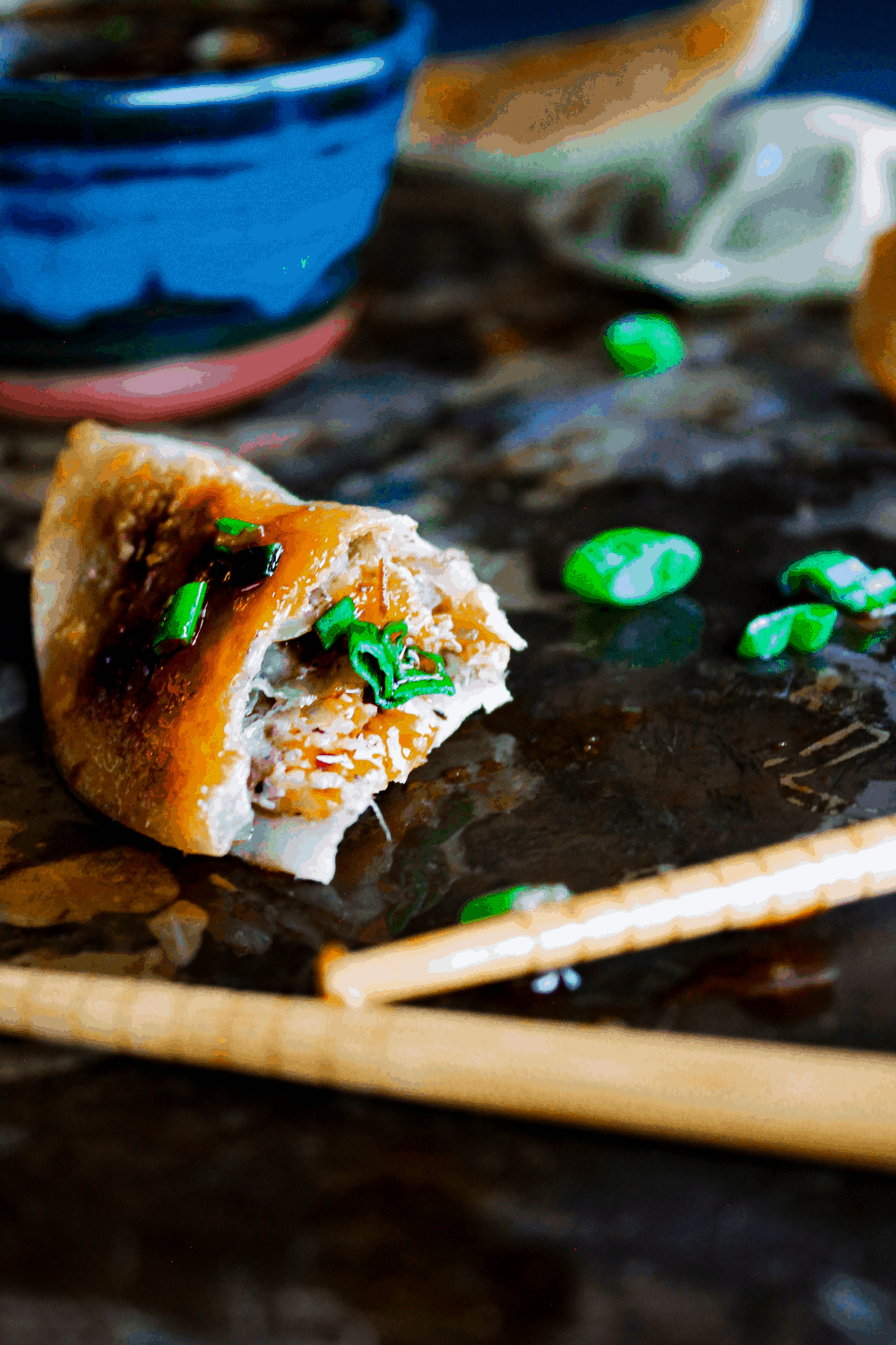 Close-up of half eaten dumplings with chopsticks and bowl of sauce.