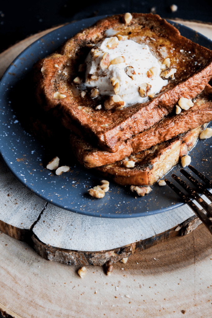 Stack of pumpkin French toast with a fork atop a stack of tree trunk platters.