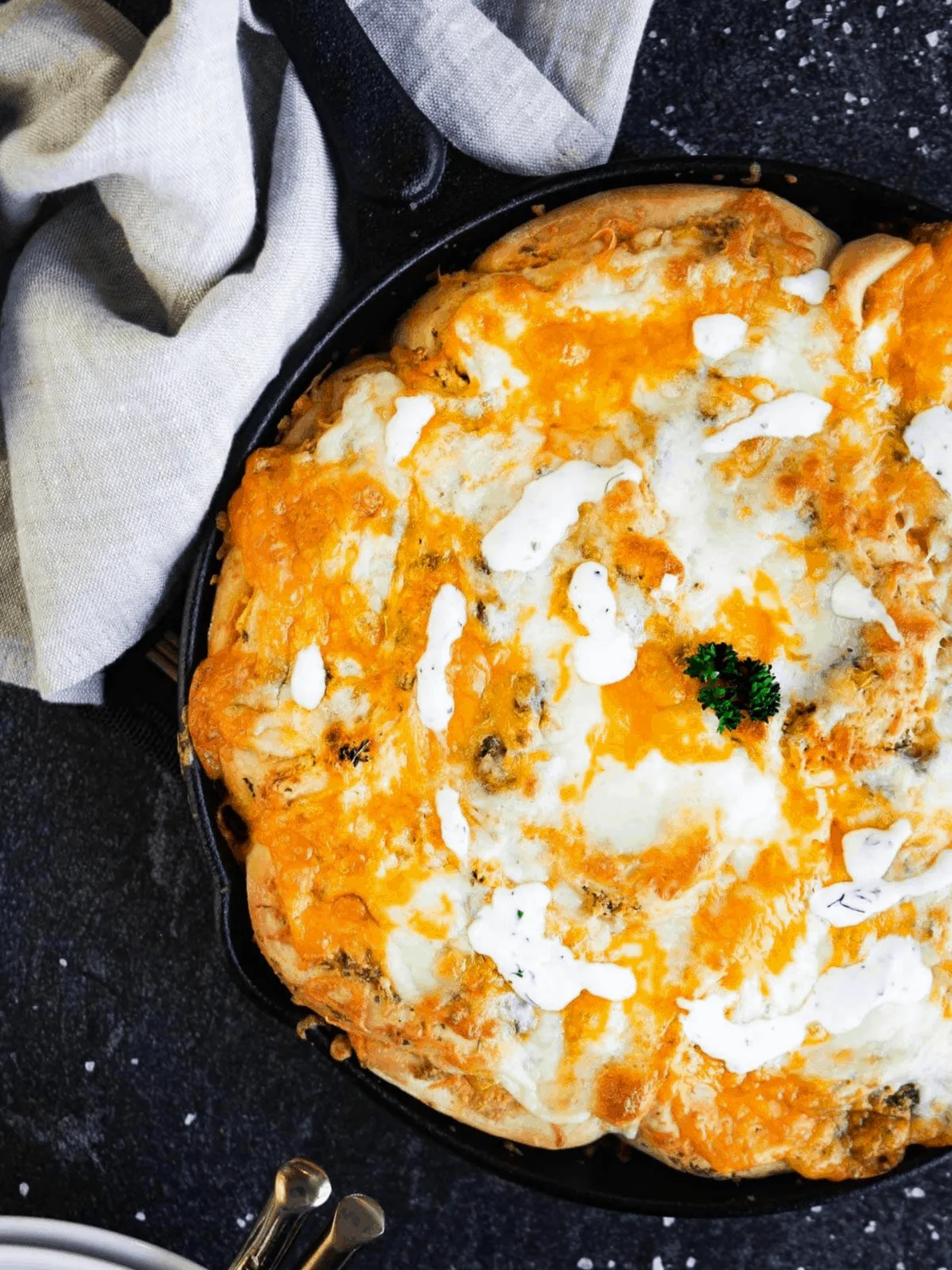 Skillet with buffalo chicken rolls and a towel.
