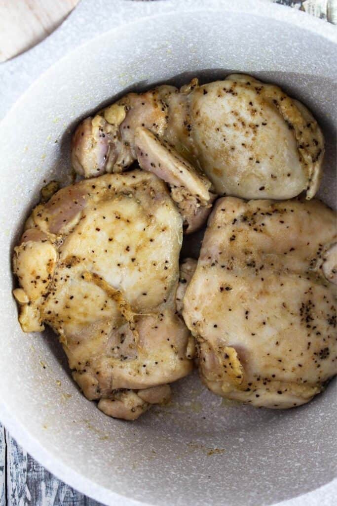 Browned chicken in a sauce pan.