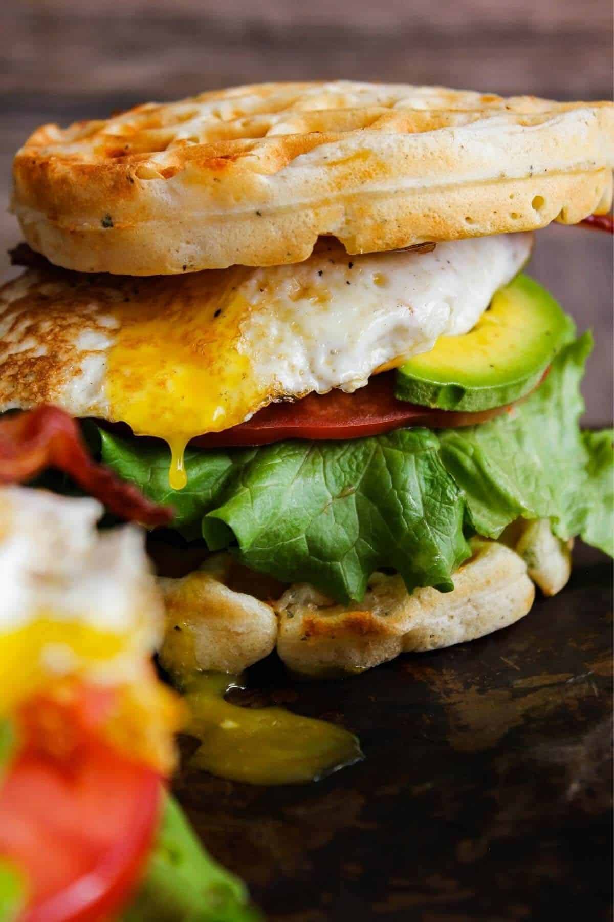 Breakfast waffle sandwich with egg yolk dripping.