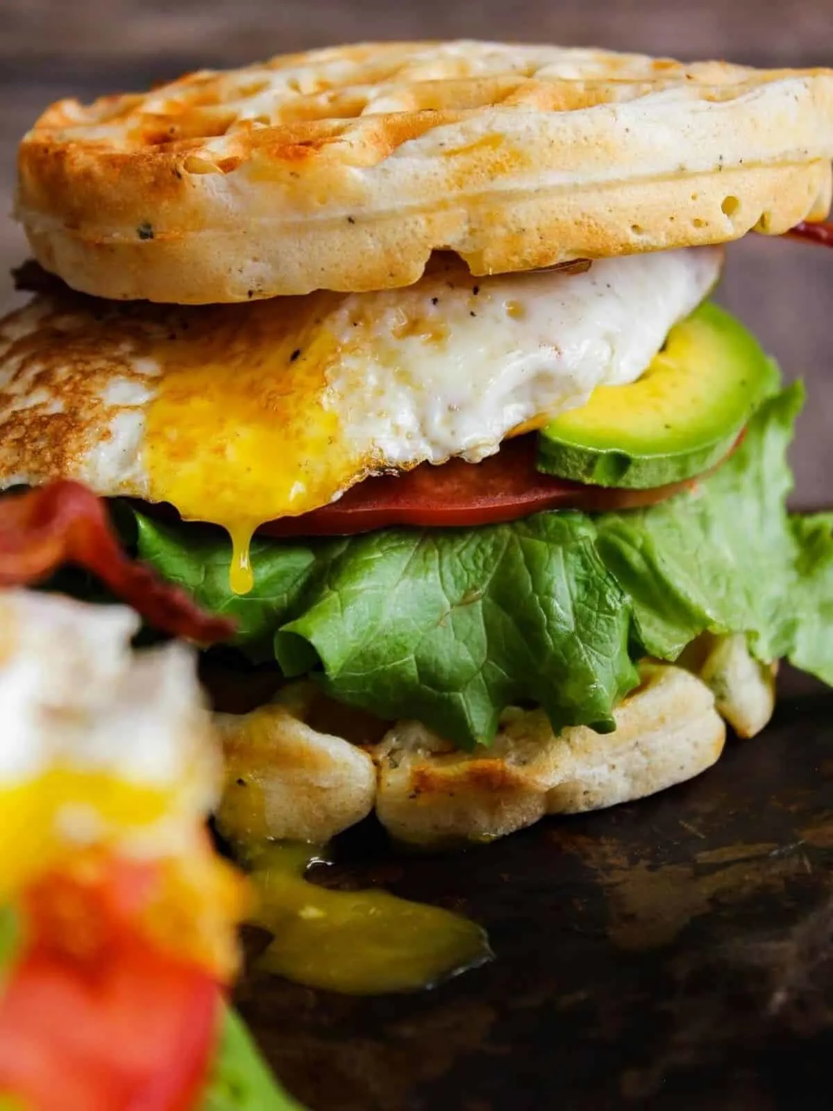 Breakfast waffle sandwich with egg yolk dripping.