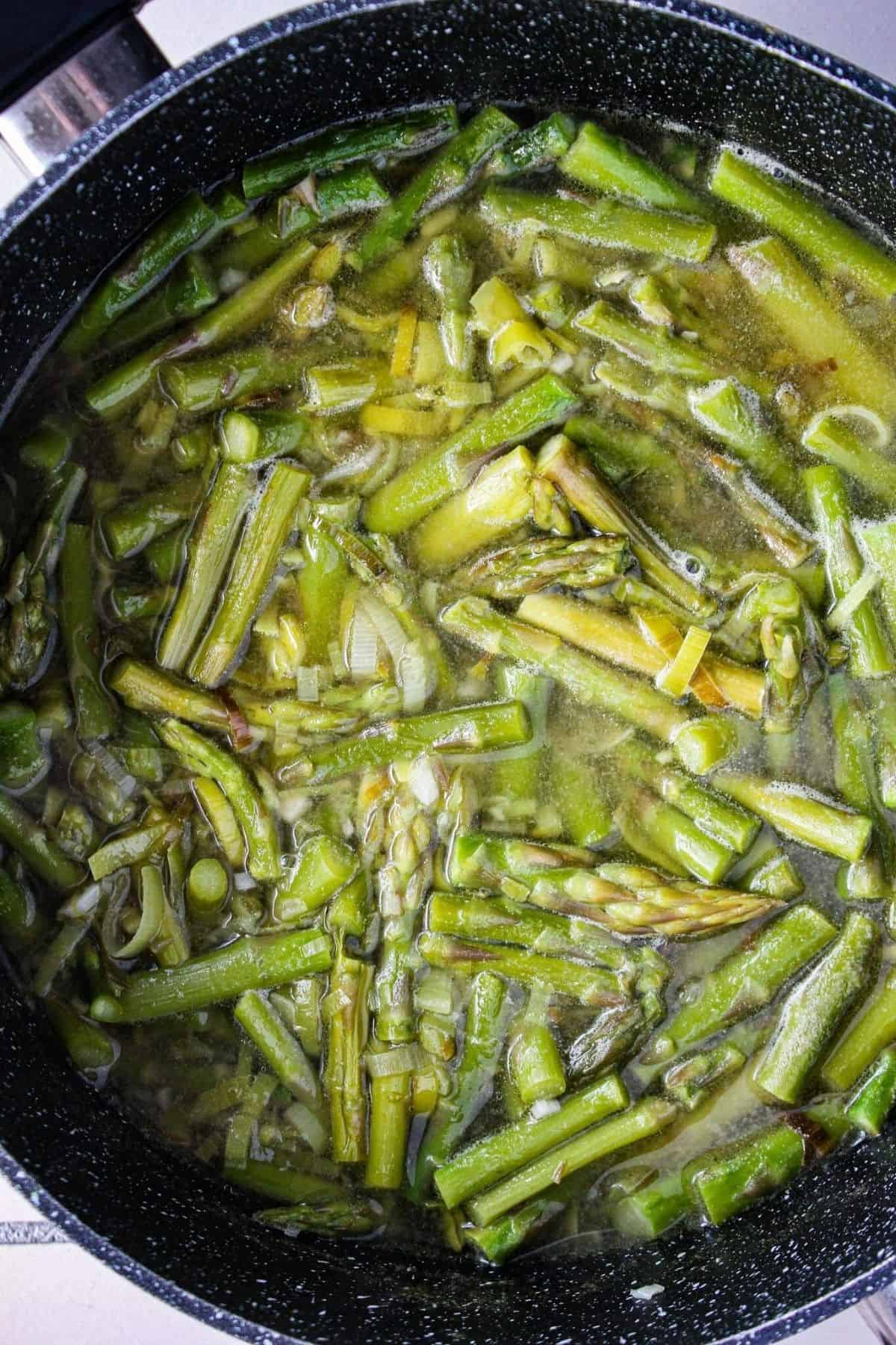 Asparagus and leeks boiling in broth.